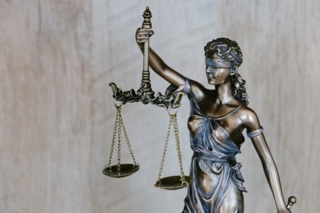 Justitia-Figur in Silber. Ihre Augen sind verbunden, sie hält eine Waage.