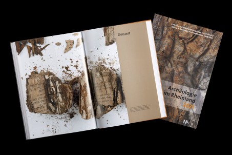 Ene Foto-Collage, bstehend aus dem Titel des Buches "Archäologie" im Rheinland und einer aufgeschlagenen Buchseite.