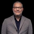 Ein Mann mit Brille und kurzem Haar lächelt in die Kamera.