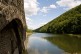 Foto: Gemauerte Wand eines Wasserkraftwerks an der Ohl. Dahinter bewaldete Hügel.