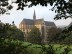 Das Foto zeigt eine große Kirche. Im Vordergrund Grünland und Büsche.