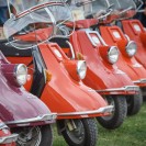 Sechs rote Motorroller aus den Sechziger Jahren, die auf einer Wiese im Freilichtmuseum stehen.