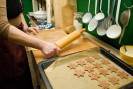 Eine Frau rollt mit einem Nudelholz Plätzchenteig aus. Im Vordergrund liegen bereits ausgestochene Sterne auf einem Backblech.