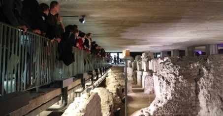 Visualisierung des Museum-Neubaus auf dem Rathausplatz in Köln: Ein unregelmäßig kubisches, sandsteinfarbenes Gebäude mit Vorplatz ist zu sehen