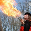 Ein Mann in einer roten Jacke spuckt Feuer.