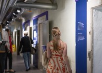Mehre Menschen stehen in einem Kellergewölbe, dort befinden sich an den Wänden Fotos und Informations-Texte.