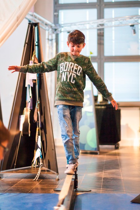 Ein Junge balanciert auf einer slackline im Museum.