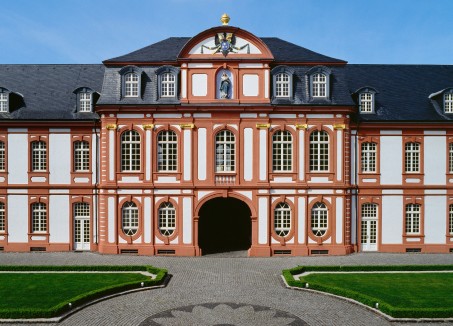 Ein großes, schönes altes Gebäude mit weißen Sprossenfenstern, vielen farbigen Verzierungen und einem grauen Dach.