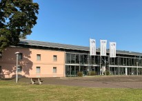Ein flaches, langgestrecktes Geb&auml;ude mit einer breiten Fensterfront.