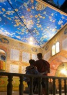 Foto: Ein sichb umarmendes Paar in Rückenansicht, vor Ihnen der freie Blick in eine aufklappbare Synagoge