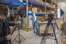 Foto: Drehsituation mit Kamera und Frau im Depot, Regale im Hintergrund