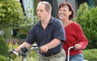 Ein Mann, der am Down-Syndrom leidet, und eine Frau fahren mit einem Tandem (Fahrrad für zwei Personen).Klick auf Foto öffnet mehr Informationen. 