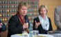 Eine Frau mit kurzen blonden Haaren hält ein Mikro in der Hand während einer Podiumsdiskussion.