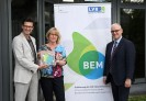 Die Personen schauen freundlich in die Kamera und halten einen Award mit der Aufschrift BEM