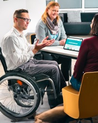 Drei Menschen sitzen am Tisch.