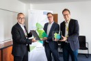 Die drei Personen schauen freundlich in die Kamera und halten eine Urkunde sowie einen Award mit der Aufschrift BEM.