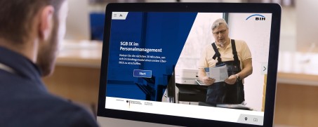 Eine Person sitzt vor einem Computerbildschirm, auf dem der Schriftzug "SGB IX im Personalmanagement" zu lesen ist.