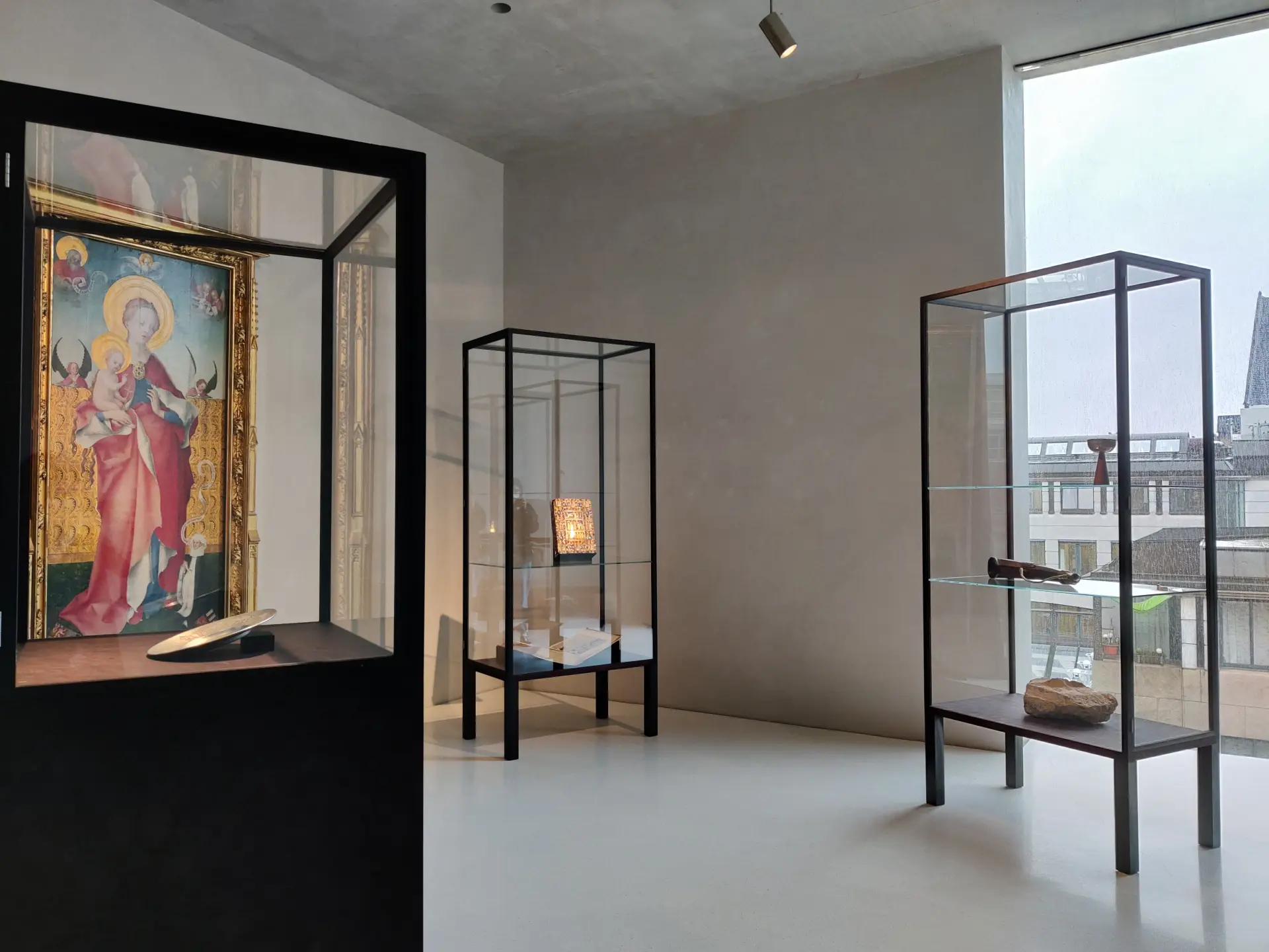 In einem Ausstellungsraum steht ein schwarzer Tisch.  An der Wand im Hintergrund ist ein modernes, grün-weißes Gemälde zu sehen.