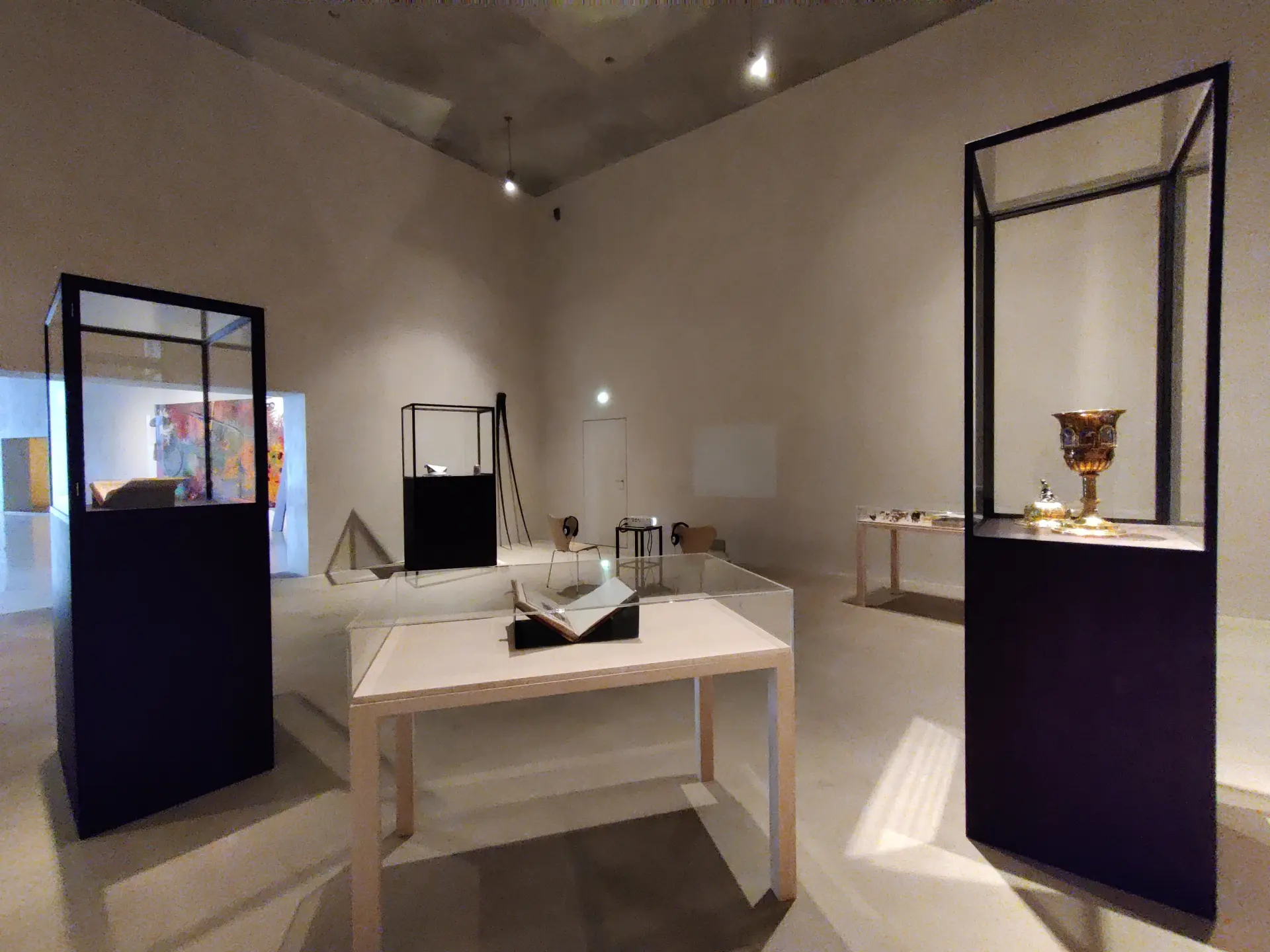 Ein heller, weißer Raum mit mehreren schwarzen Vitrinen.  Ein weißer Tisch mit einem Ausstellungsstück.