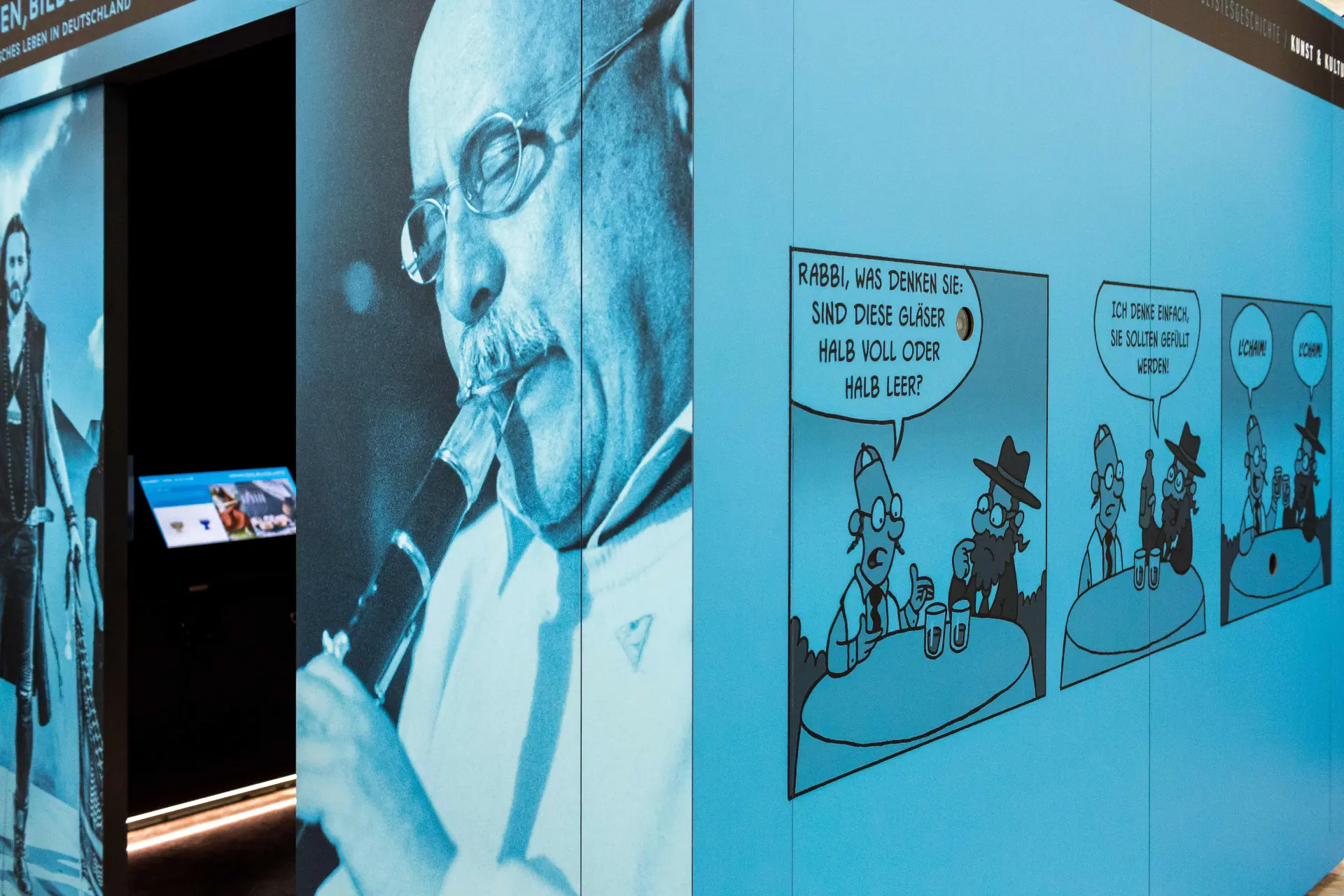 Ein Blick hinein in den blauen Ausstellungskubus. Im Innenraum des Kubus sind Displays angebracht.