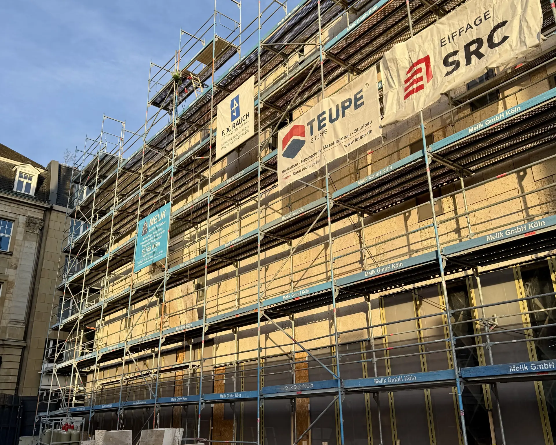 Eine Gebäude mit einer weißen Steinfassade.  Ein Baugerüst ist zu sehen.