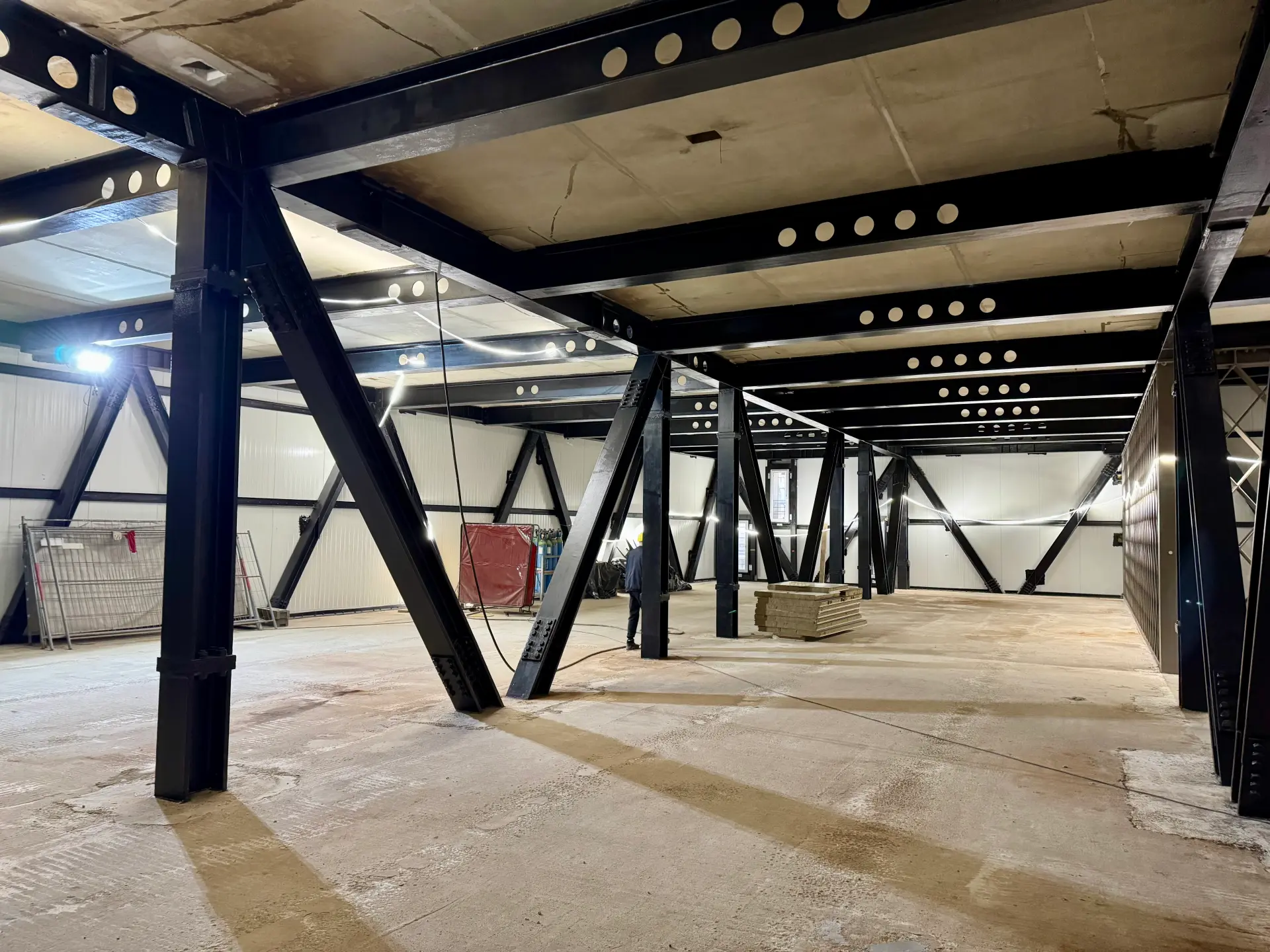 Auf einer Baustelle blickt man in einen Raum, wo Stahlrauten als Stützen der Decke zu sehen sind.