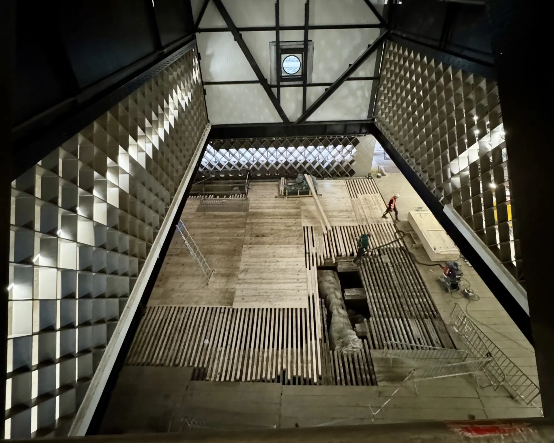 Auf einer Baustelle blickt man vom Obergeschoss auf einen großen, offenen Raum im Erdgeschoss.