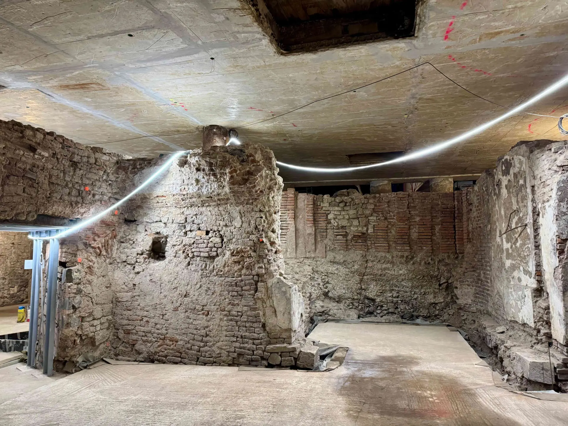 Sandsteinfarbene Kellerwände in der Ausgrabung des jüdischen Viertels.  Beleuchtet wird mit einer LED-Lichterkette.