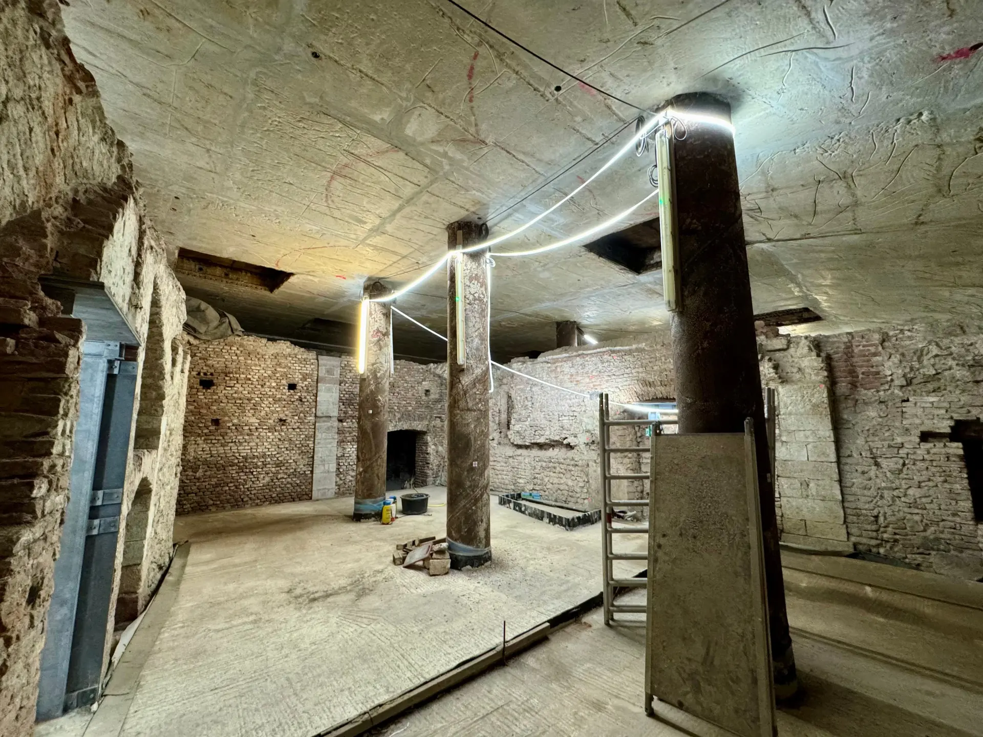 Sandsteinfarbene Kellerwände in der Ausgrabung des jüdischen Viertels.  Beleuchtet wird mit einer LED-Lichterkette