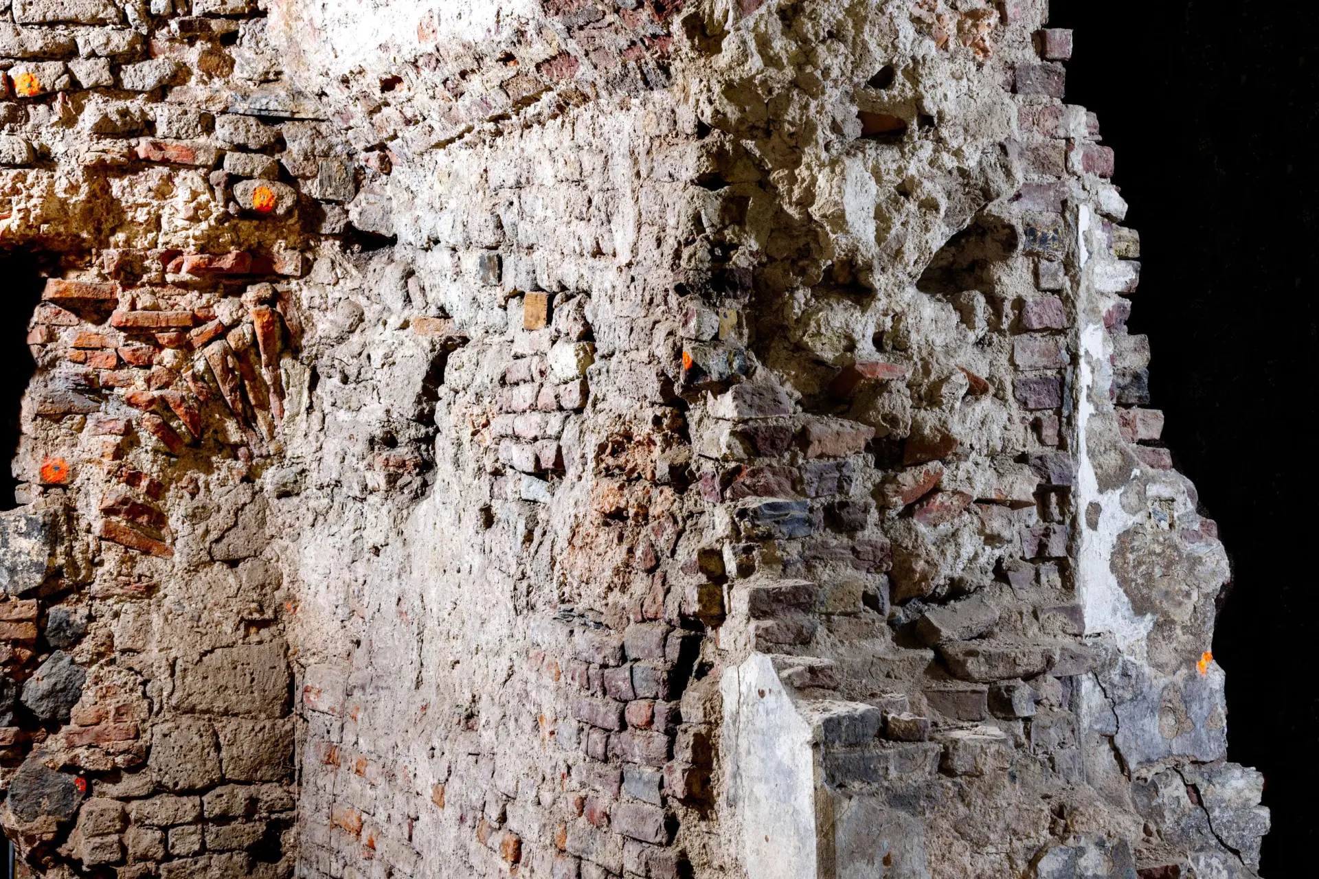 Eine zum Teil eingefallen sandfarbene Wand eines Kellers.