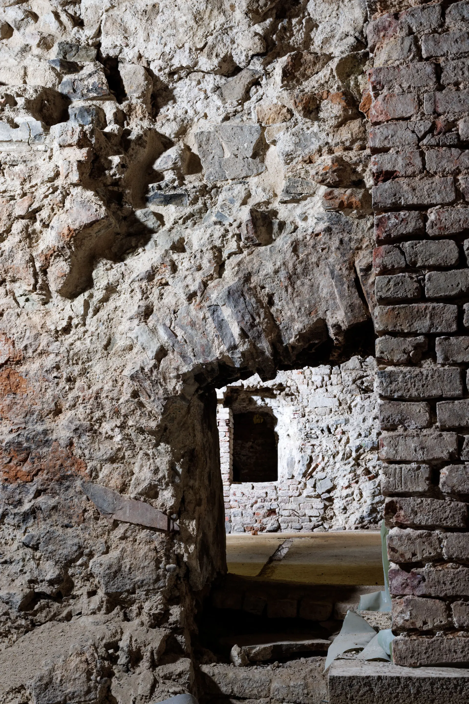 Eine Öffnung in einer Kellerwand lässt in den nächsten Raum einblicken.