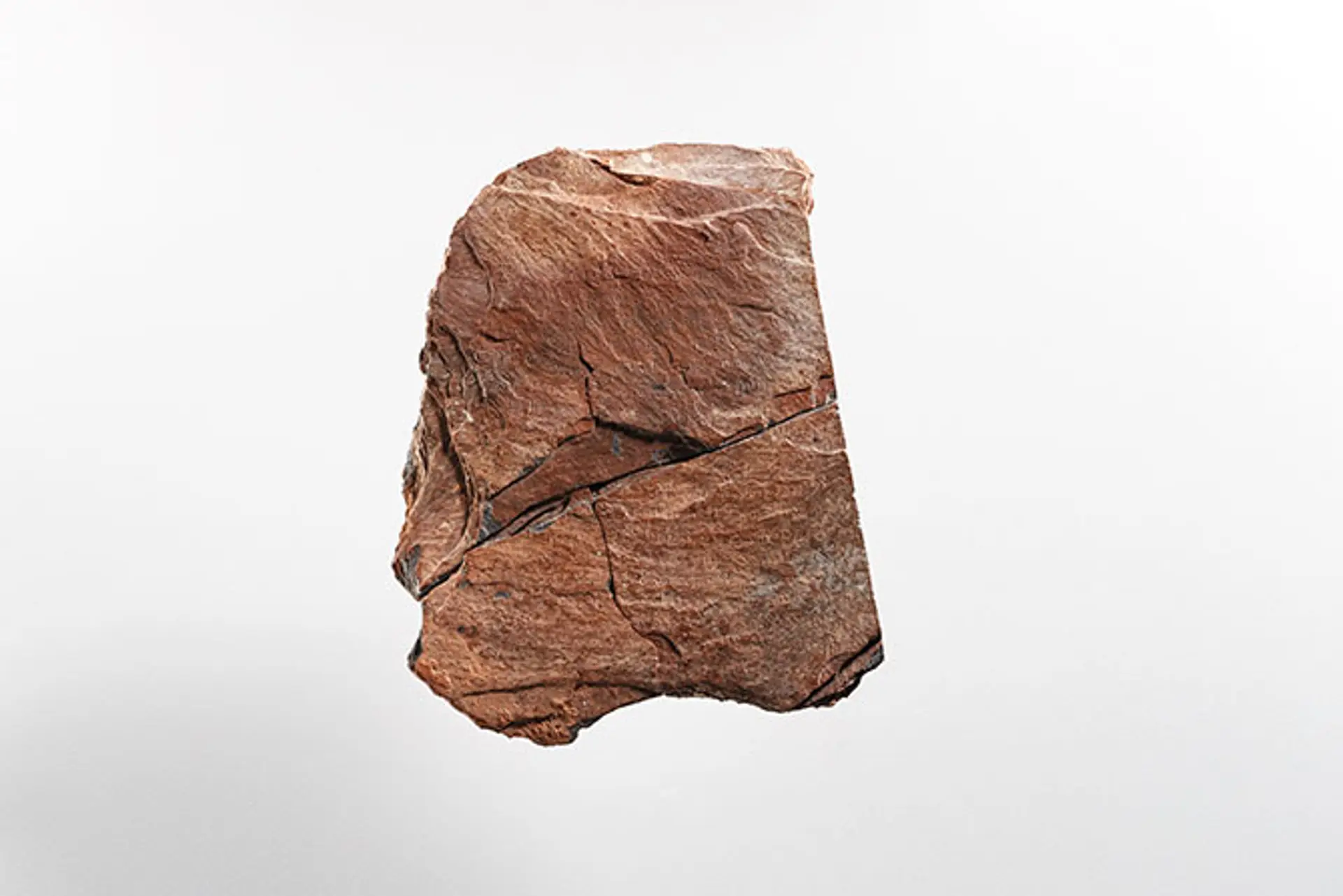 Ein Stück einer roten Schiefertafel mit eingeritzten Zeichen.