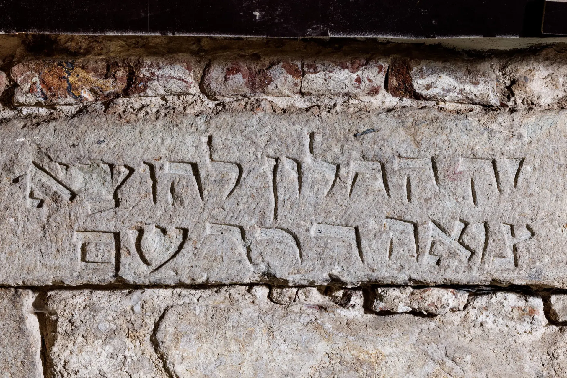 Ein Hibräische Inschrift ist in eine graue Fassade eingemeißelt.