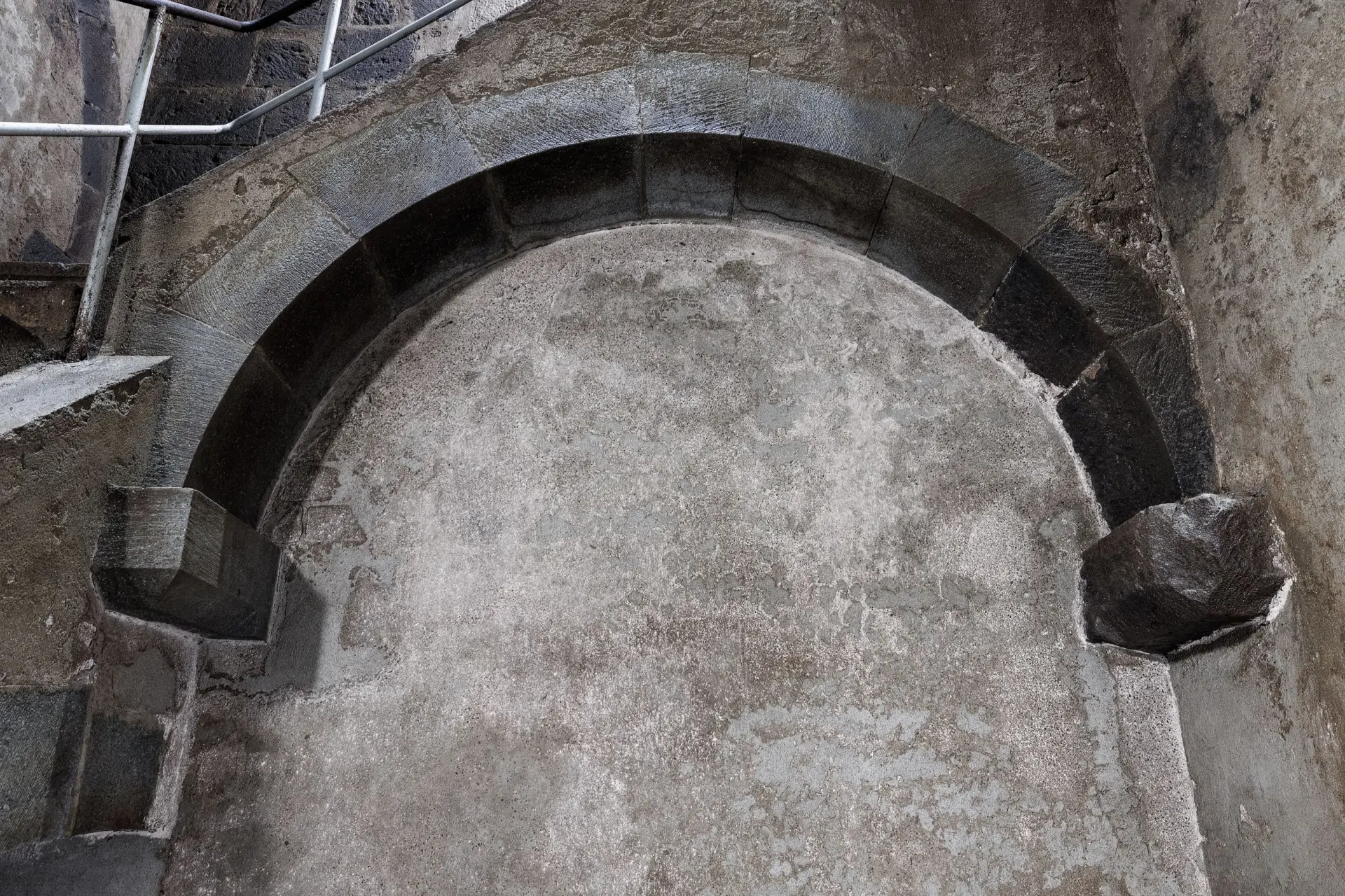 Ein Bogengang aus grauem Stein ist zugemauert.