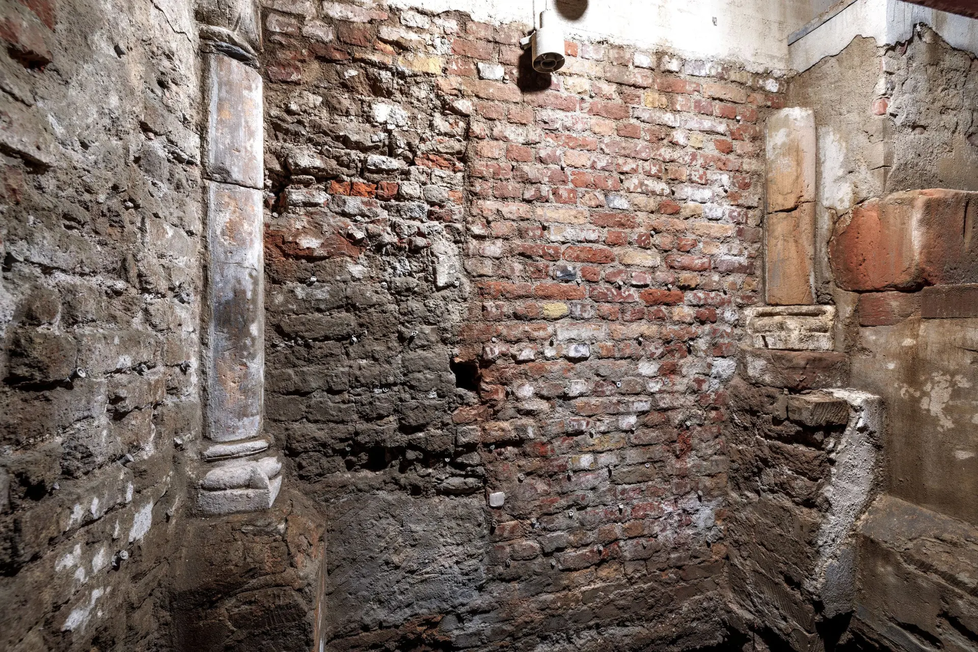 Eine Backsteinwand.  Links ist eine Säule zu sehen.