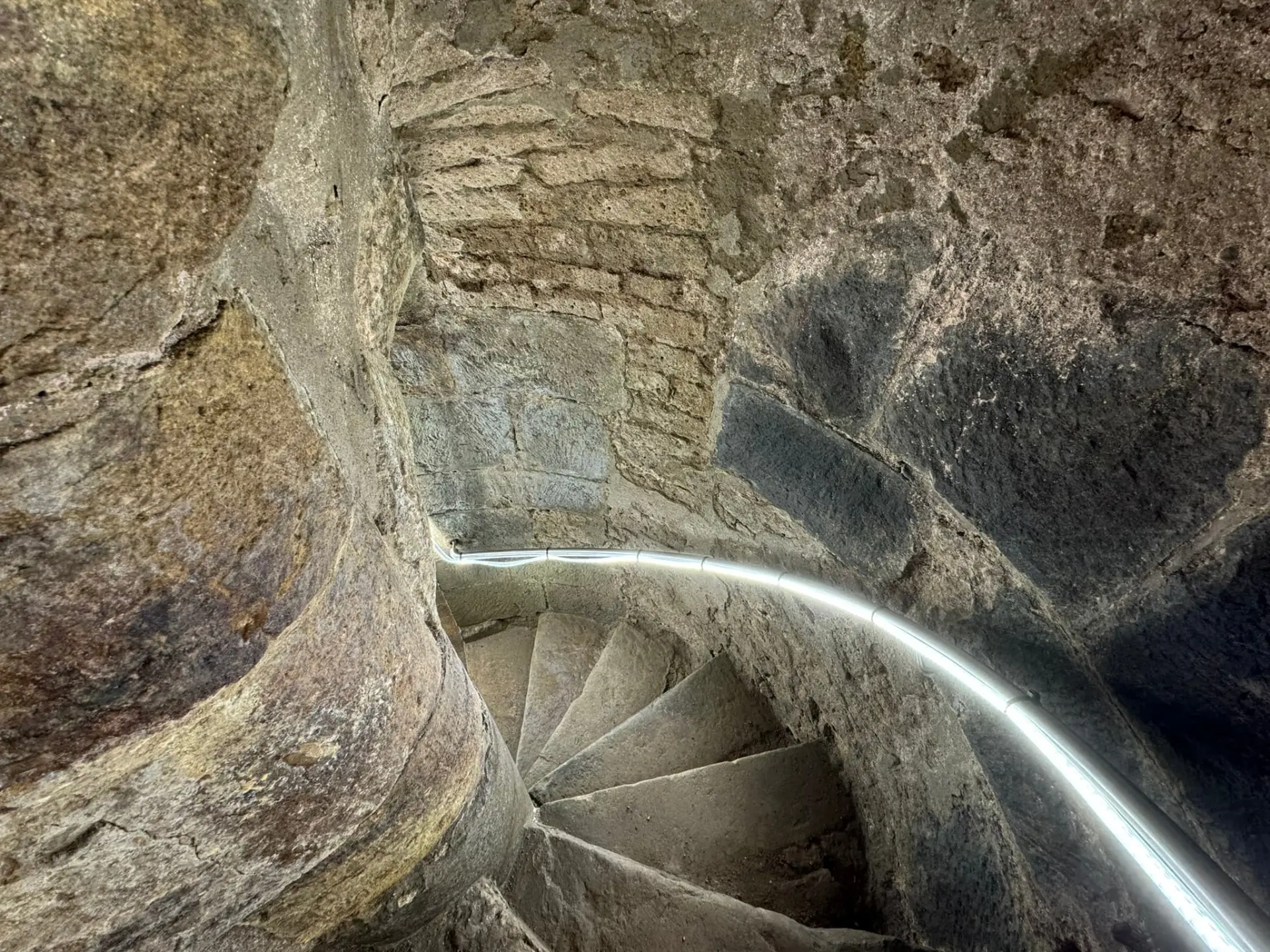 Eine graue Steintreppe führt nach unten.  Beleuchtet wird mit einer Lichterkette.