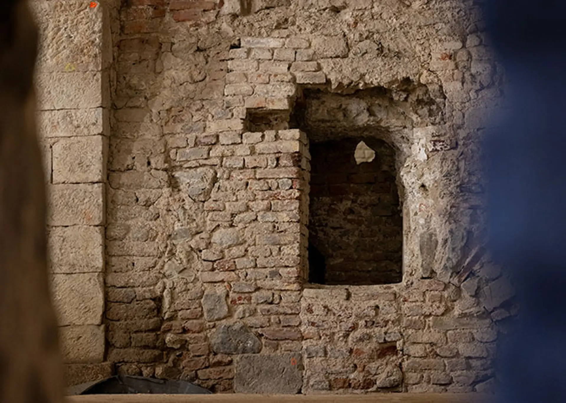 Eine Öffnung in einer Kellerwand lässt in den nächsten Raum einblicken.