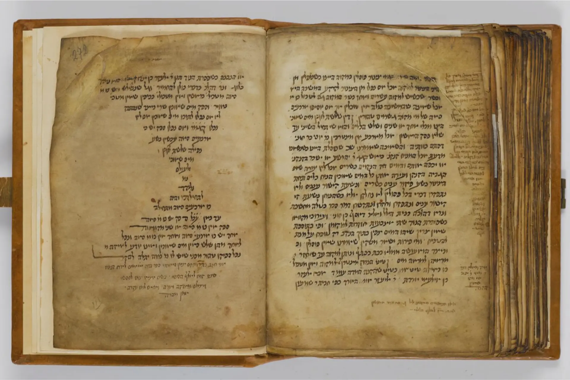 Ein aufgeklapptes, altes Buch zeigt sehr alte Seiten mit hebräischen Schriftzeilen.