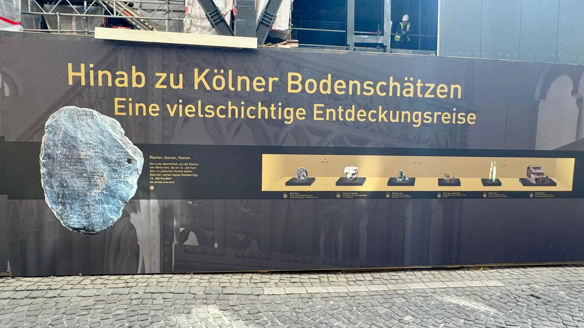 In einem Schaufenster sieht man historische Objekte.  Das Schaufenster ist gold und schwarz.