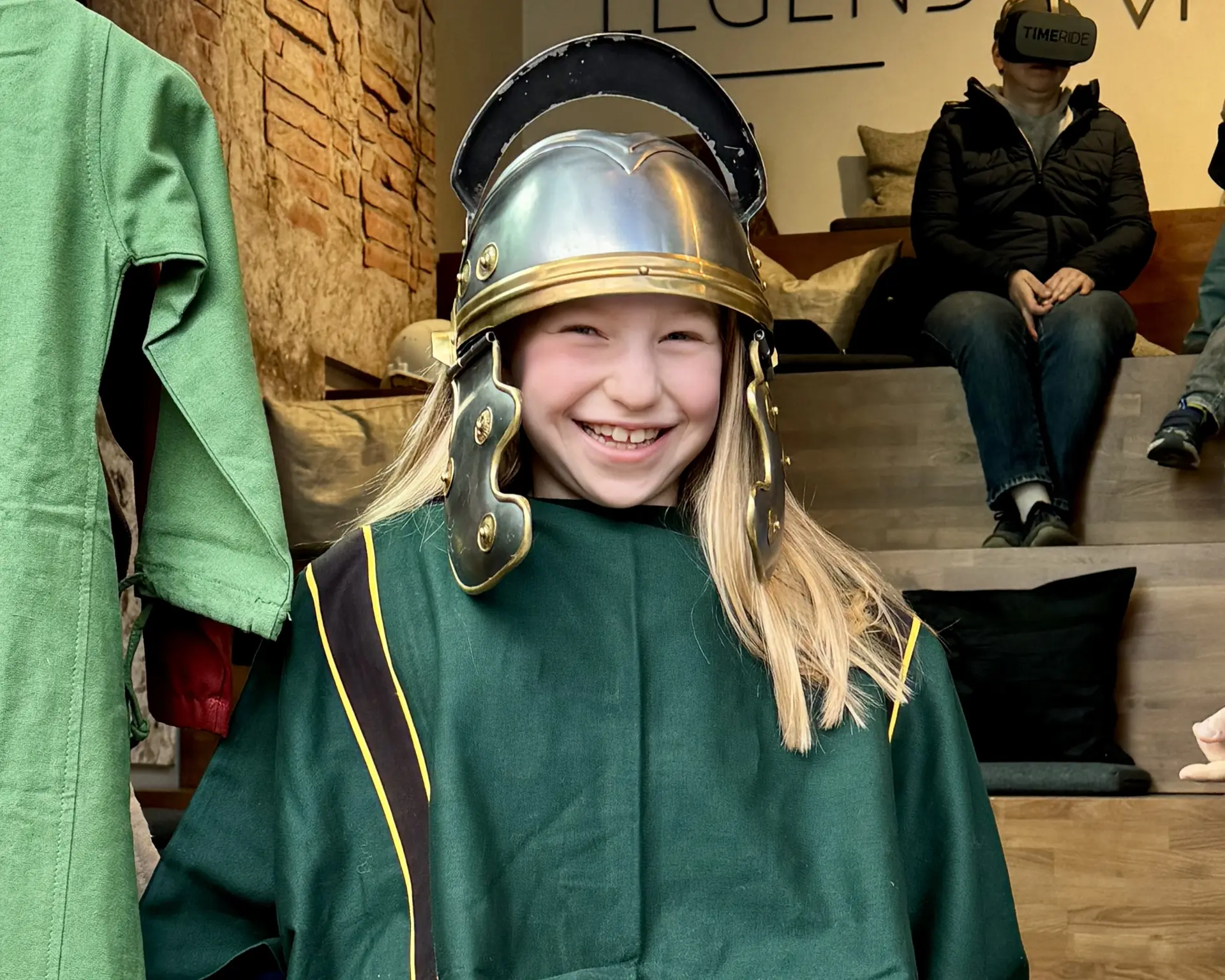 Ein Kind trägt eine grüne Toga und einen silbernen Metallhelm.