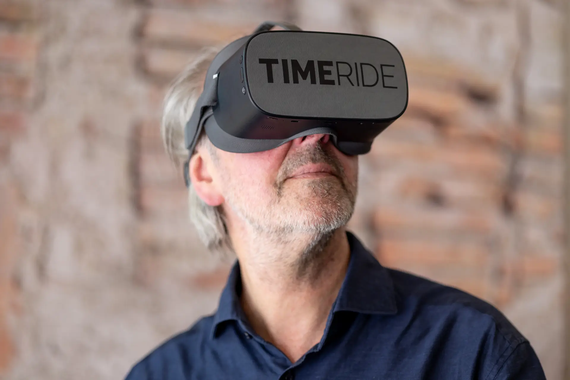 Ein Herr trägt eine große, dunkle Brille auf der TimeRide steht.