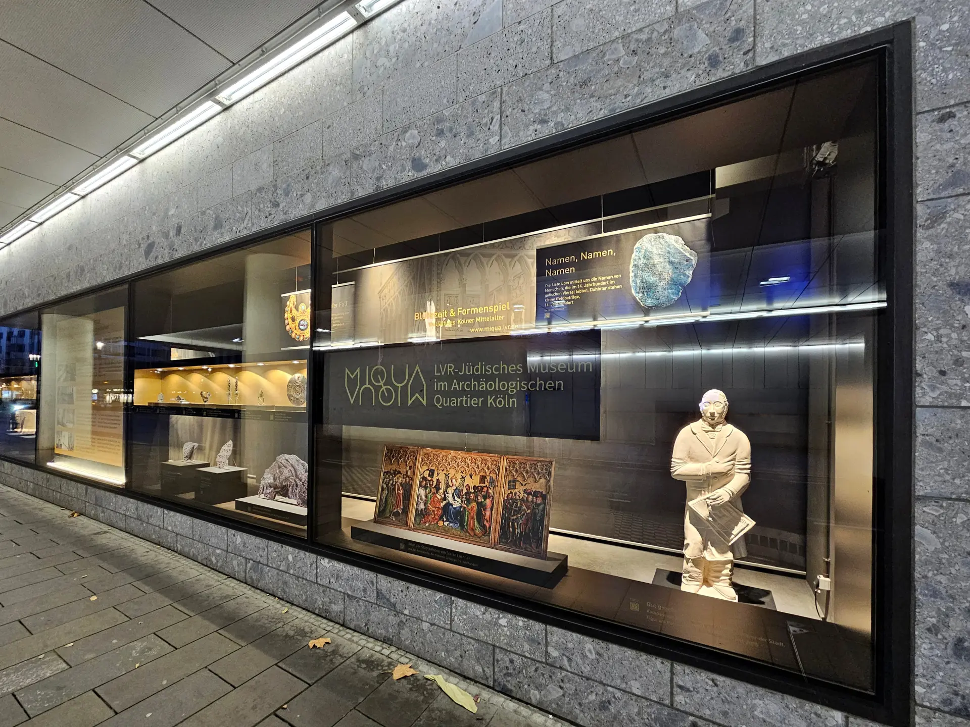 In einem Schaufenster sieht man historische Objekte.  Das Schaufenster ist gold und schwarz.