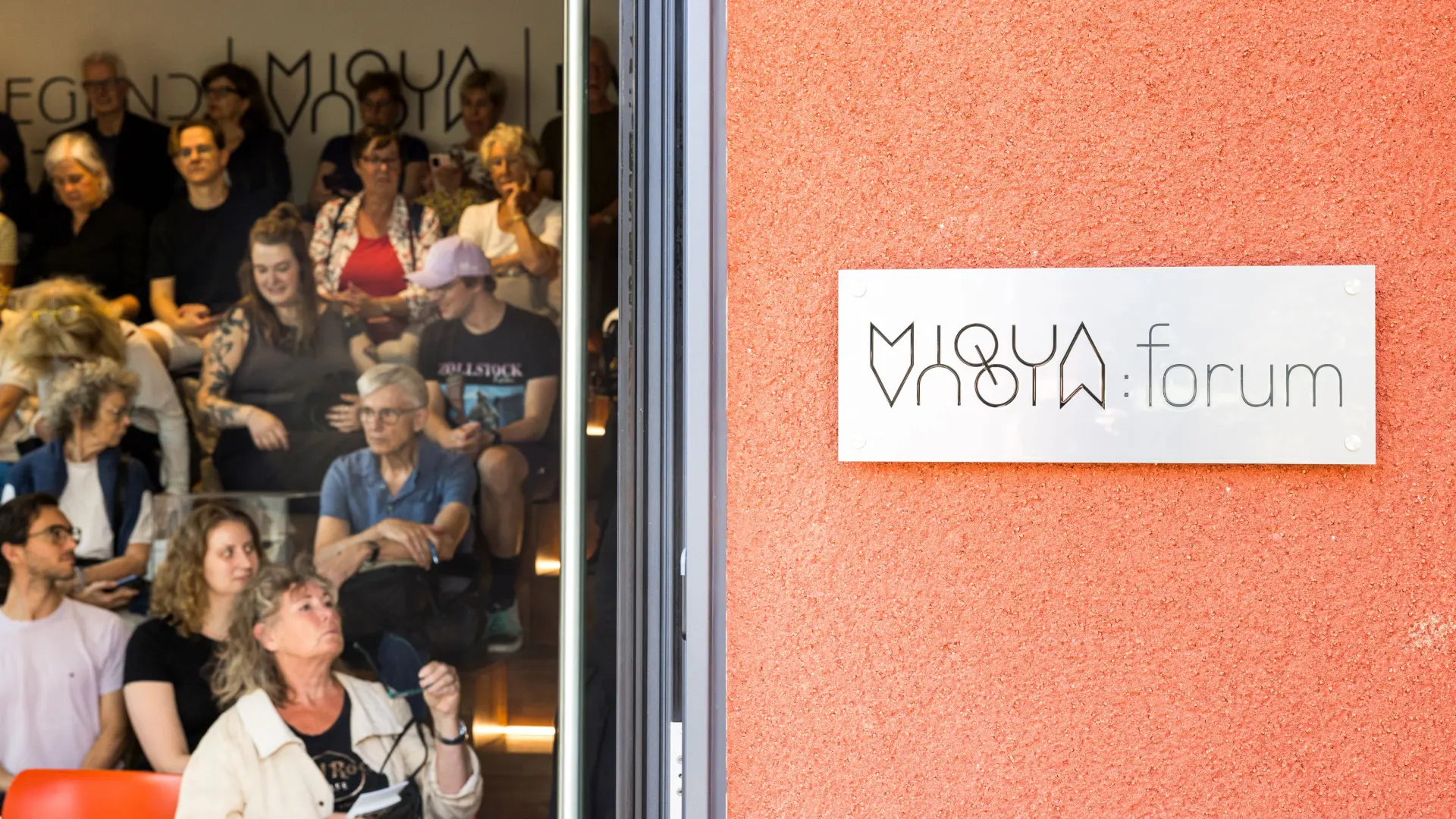 Eine Gruppe Menschen sitzt auf einer Treppe in einem Gebäude.