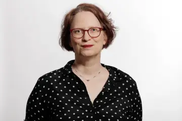 Ein Dame mit braunen Haaren und einer Brille lächelt in die Kamera