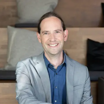 Ein Mann sitzt auf einer Treppe und lächelt in die Kamera.