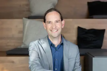 Ein Mann sitzt auf einer Treppe und lächelt in die Kamera.