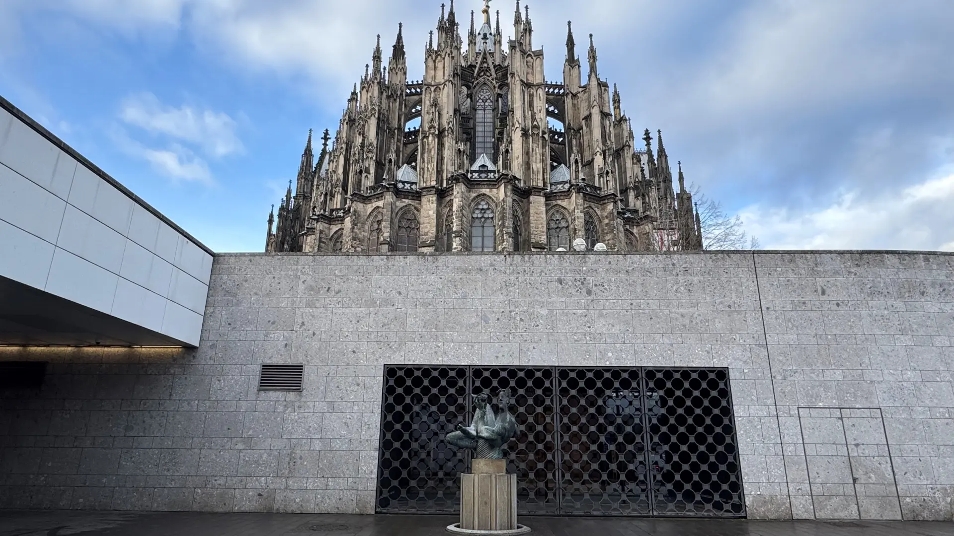 Ein Eingang in ein Gebäude. Dahinter ist eine große Kirche zu sehen.