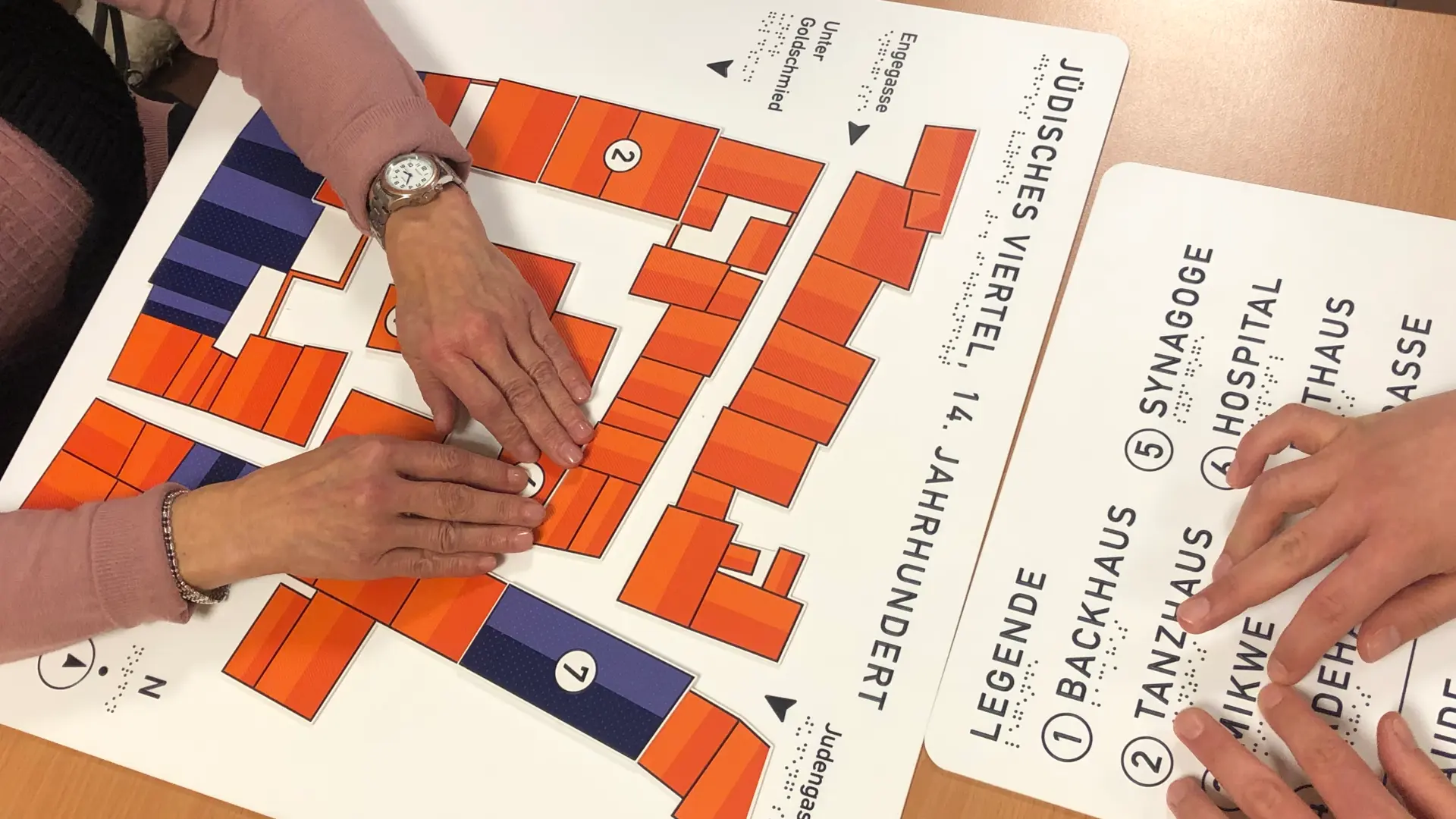 Ein Tastplan mit roten und blauen Rechtecken und zwei paar Händen.