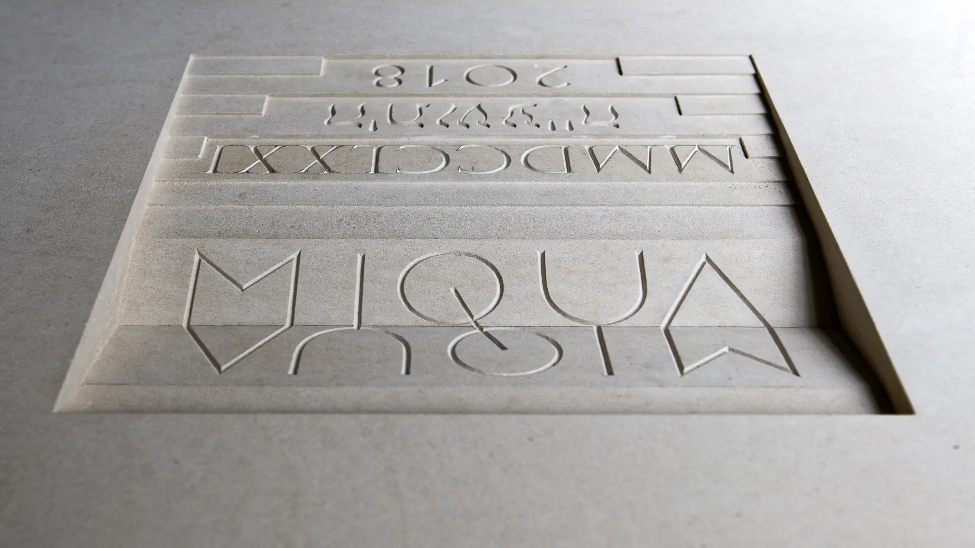 Ein quadratischer, weißer Stein auf dem MiQua steht.