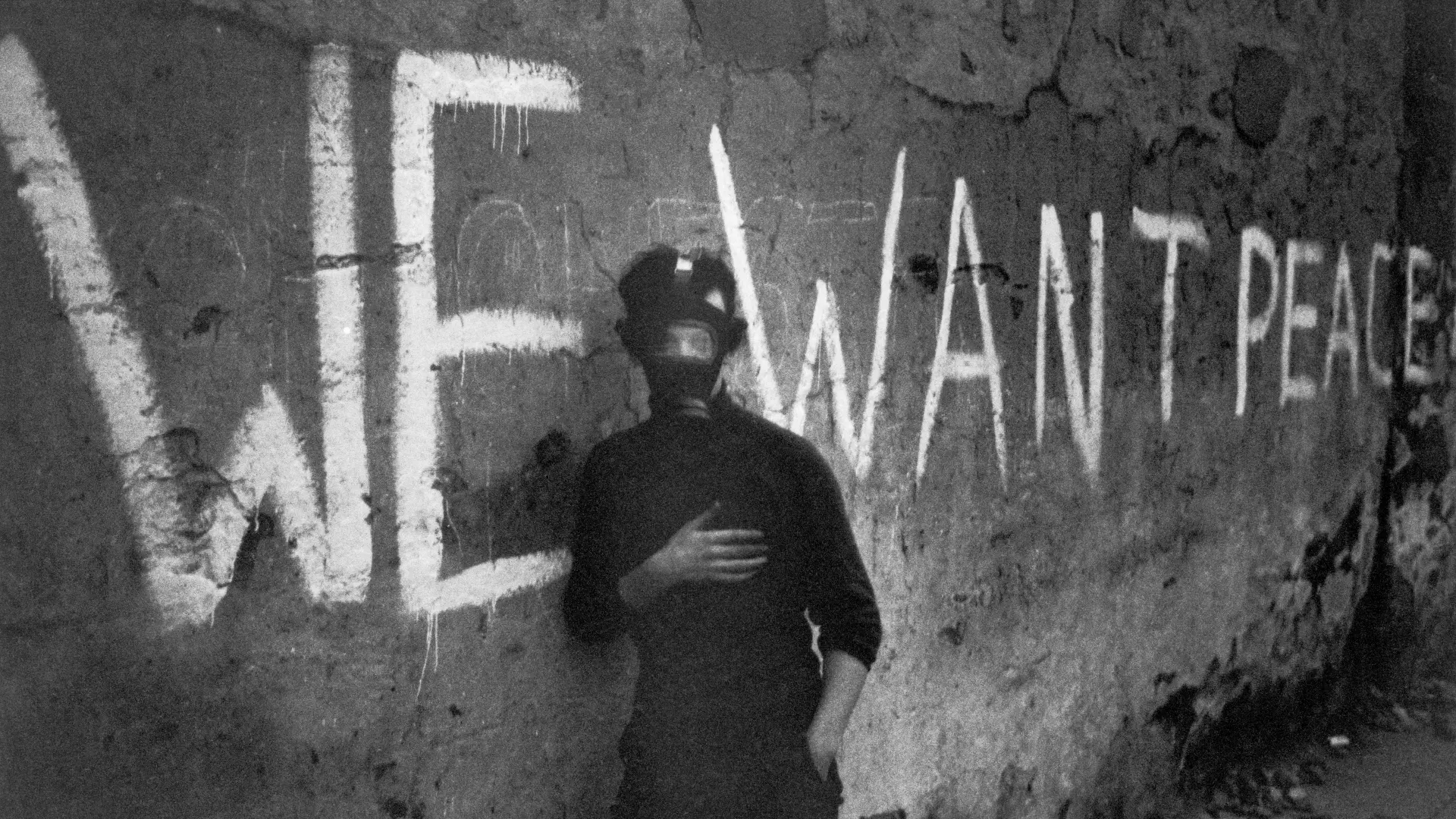 Das Bild zeigt einen Mann vor einem Graffito